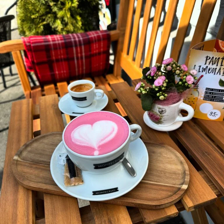 Růžové latte se srdíčkem a šálek espressa na dřevěném stolku venkovního posezení kavárny GP Caffé
